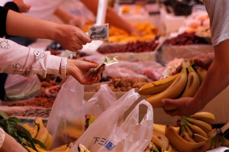FILE PHOTO: Customers pay money as they purchase bananas at a market in Beijing
