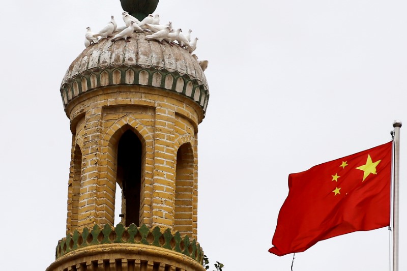 A Chinese national flag flutters near a minaret of the ancient Id Kah Mosque in the Old City in Kashgar