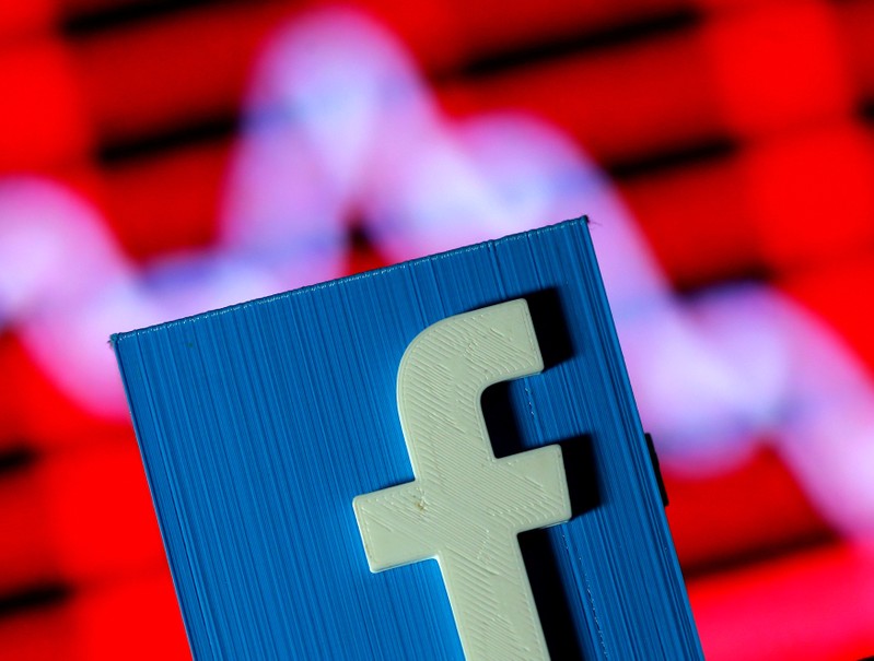 A 3D-printed Facebook logo is seen in front of a displayed stock graph in this illustration taken