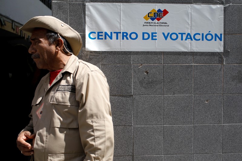 A militia member stands guard at a polling station during the municipal legislators election in Caracas