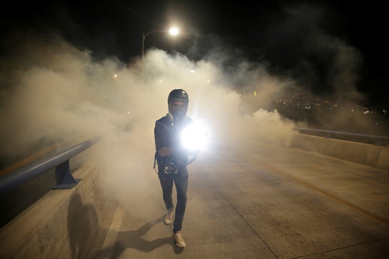 FILE PHOTO: A cameraman is seen amidst tear gas during a protest to mark the first anniversary of a contested presidential election with allegations of electoral fraud, in Tegucigalpa