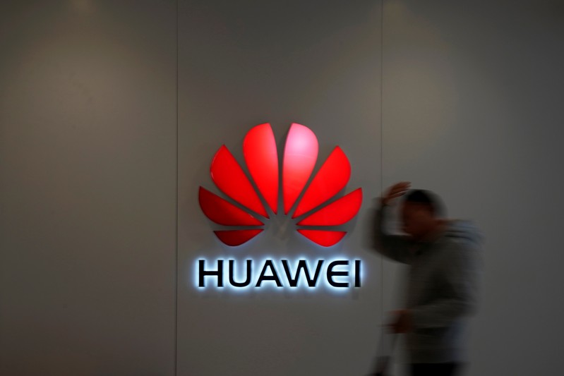 Man walks by a Huawei logo at a shopping mall in Shanghai
