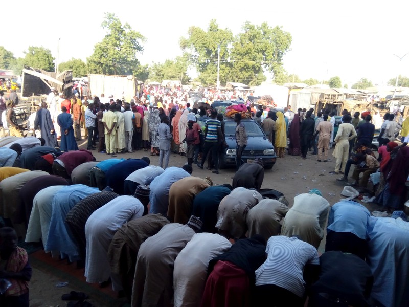 People are seen praying as others fleeing the town of Baga arrive to Maiduguri