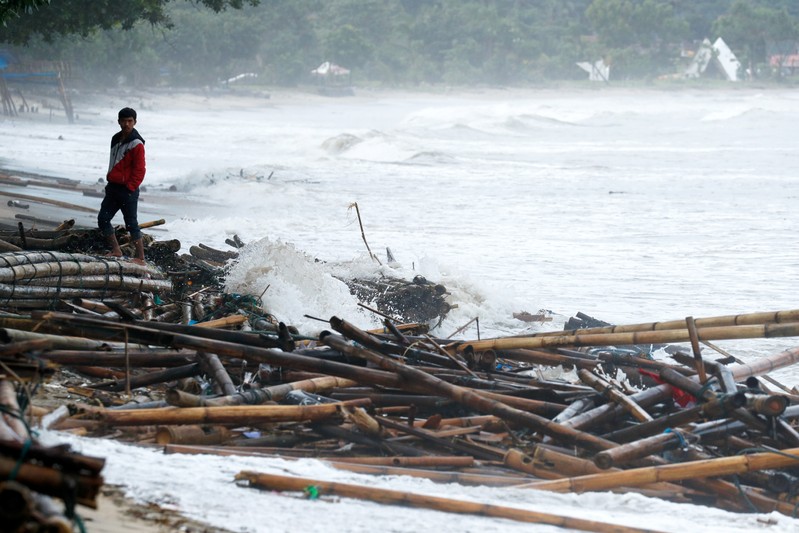 A local resident affected by the tsunami stands next to debris in Carita beach in Pandeglang