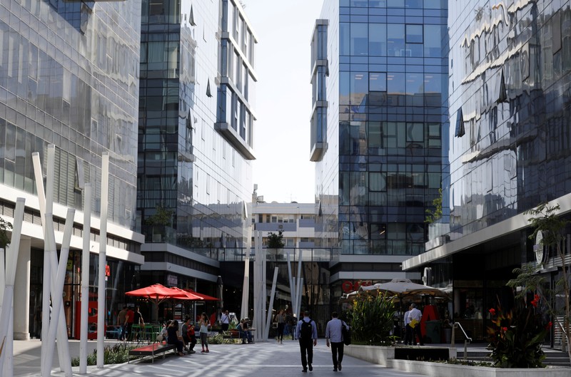 FILE PHOTO: Men walk near high-rise buildings in the high-tech business area of Tel Aviv, Israel