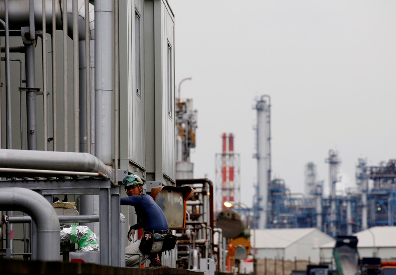 FILE PHOTO : A worker is seen in front of facilities and chimneys of factories at the Keihin Industrial Zone in Kawasaki