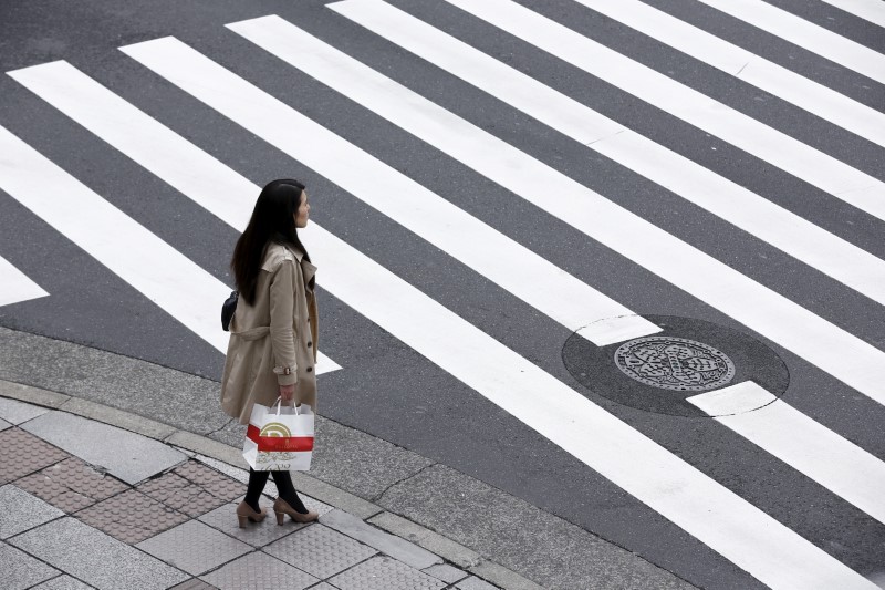 A woman holds a shopping bag as she waits at a pedestrian crossing in the Ginza district in Tokyo