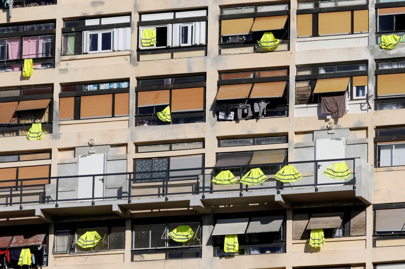 Yellow vests are hung outside windows of an apartment building in support of the 
