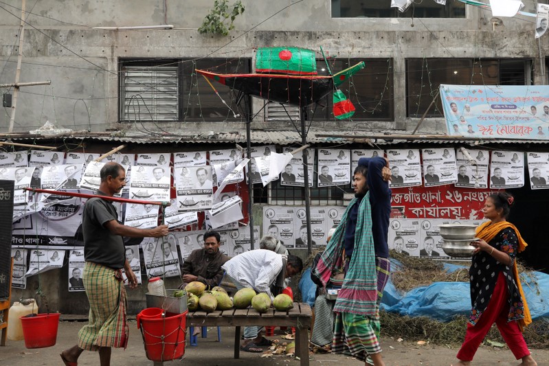 Posters and a replica of a boat, the voting symbol of Bangladesh Awami League, are seen as people walk on a street in Dhaka