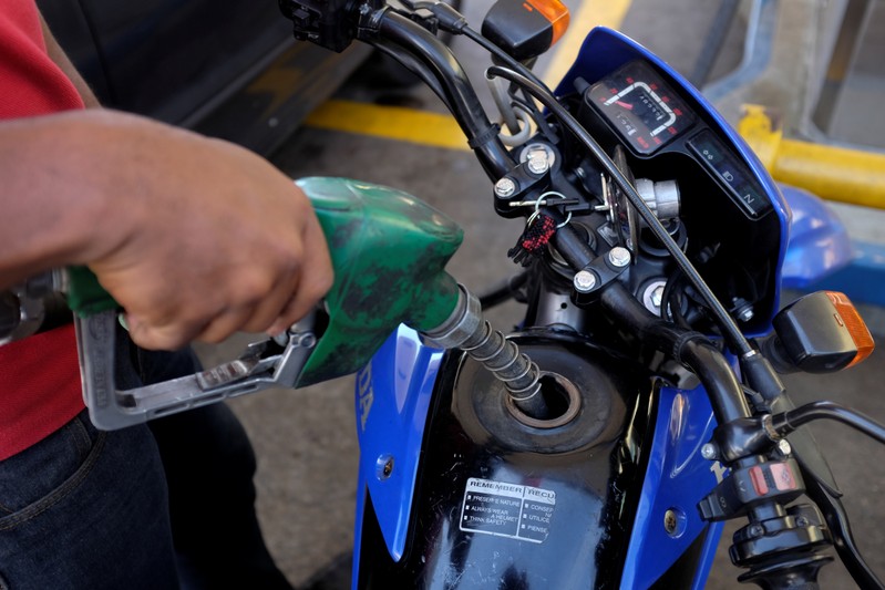 A gas station worker pumps fuel into a motorbike at a gas station of the Venezuelan state-owned oil company PDVSA in Caracas