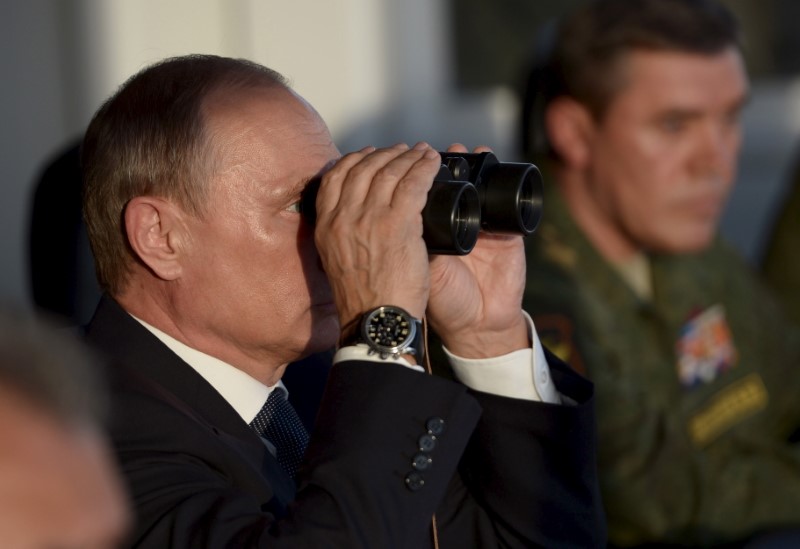 Russian President Vladimir Putin uses a pair of binoculars to observe troops in action during a training exercise at the Donguz testing range in Orenburg region, Russia