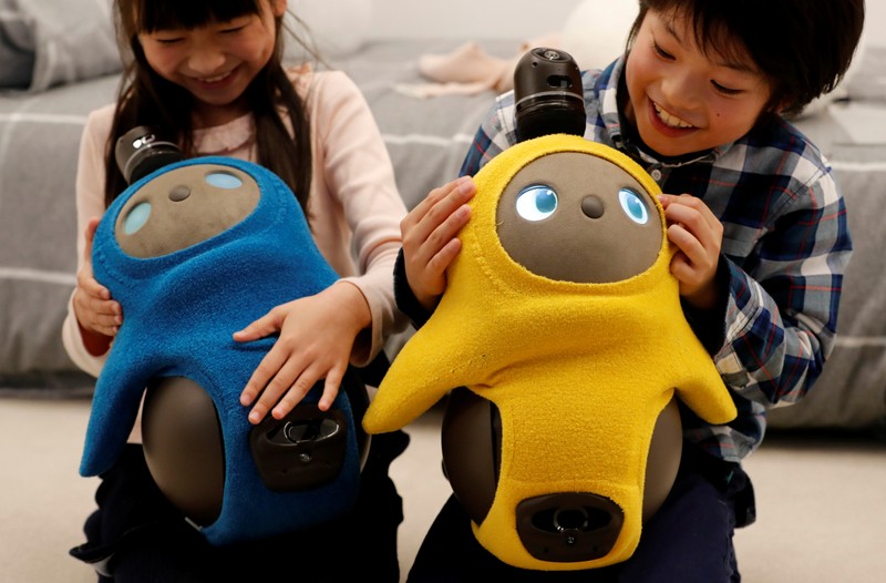 Children hold GROOVE X's new home robot LOVOT at its demonstration during the launching event in Tokyo