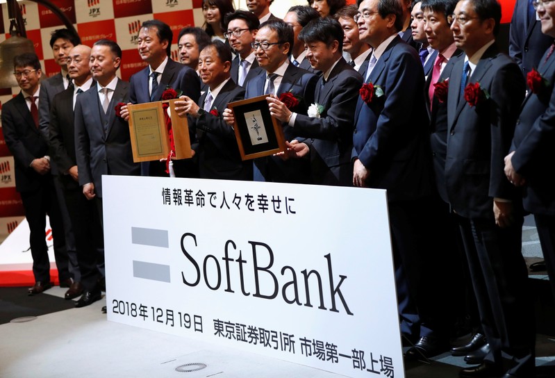 SoftBank Corp. President and CEO Ken Miyauchi poses as he holds an IPO certificate with Tokyo Stock Exchange director and executive officer Yasuyuki Konuma during a ceremony to mark the company's debut on the Tokyo Stock Exchange in Tokyo