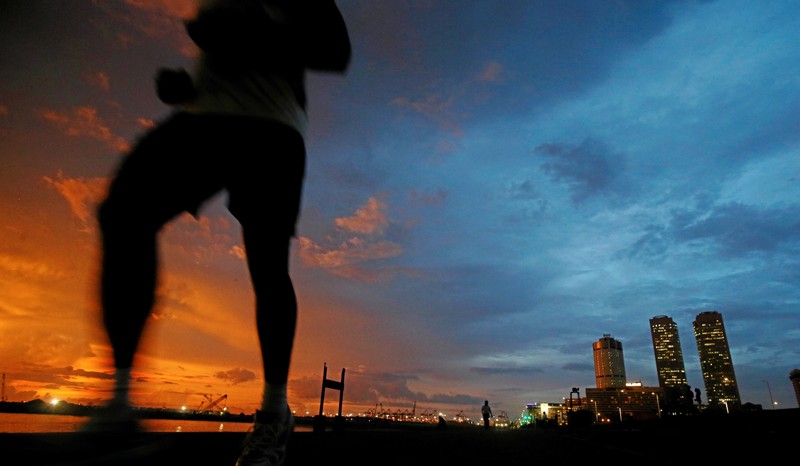 Financial district of Colombo is seen as a man runs along a path in front of the China invested Colombo Port City construction site in Colombo