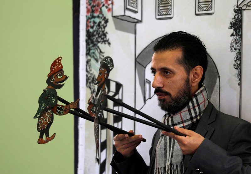 Shadi al-Hallaq, a puppeteer, holds two puppets during a performance in Damascus