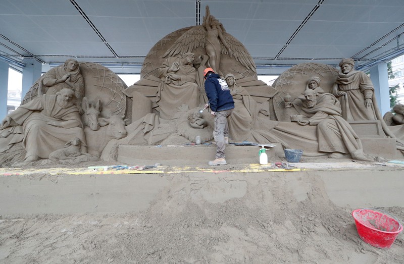 An artist works on a sand sculpture representing part of nativity scene in St. Peter's square at the Vatican