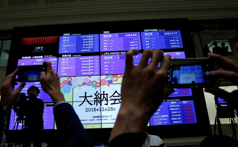 FILE PHOTO: Attendees take pictures of a stock quotation board after a ceremony marking the end of trading in 2018 at the Tokyo Stock Exchange (TSE) in Tokyo