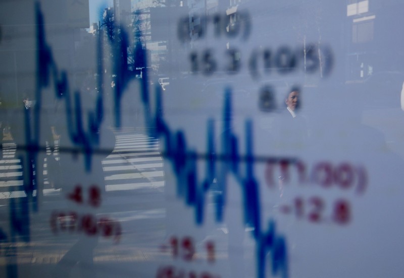 A man is reflected on an electronic board showing a graph analyzing recent change of Nikkei stock index outside a brokerage in Tokyo