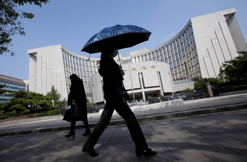 FILE PHOTO: People walk past the headquarters of the PBOC, the central bank, in Beijing