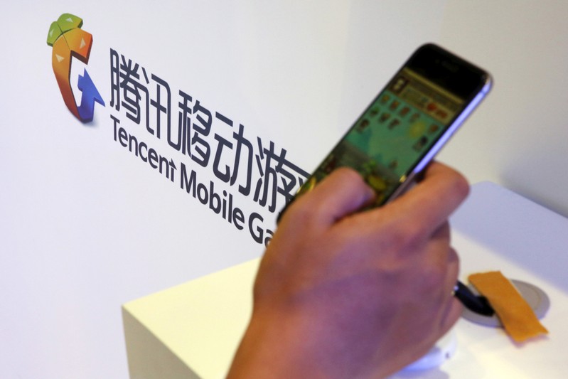 FILE PHOTO: Visitor plays a game on a smartphone at Tencent's exhibition booth at the Global Mobile Internet Conference (GMIC) 2015 in Beijing