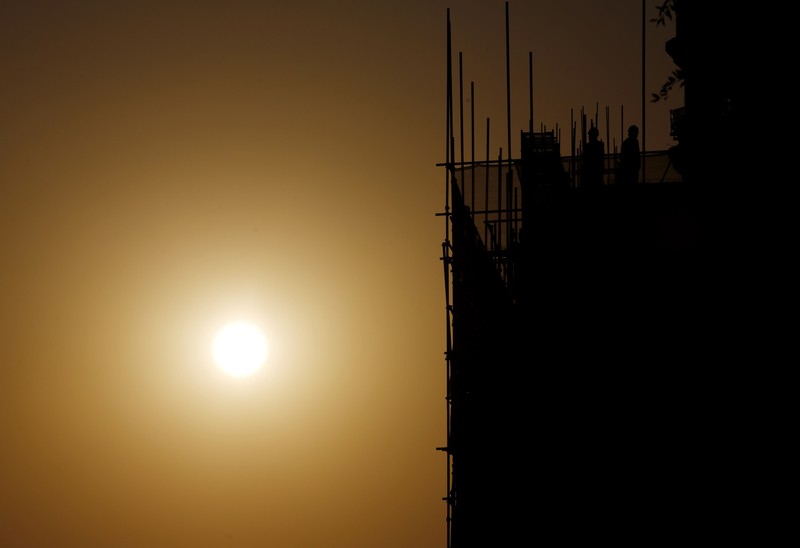 Labourers working on a construction site are seen next to setting sun in Beijing