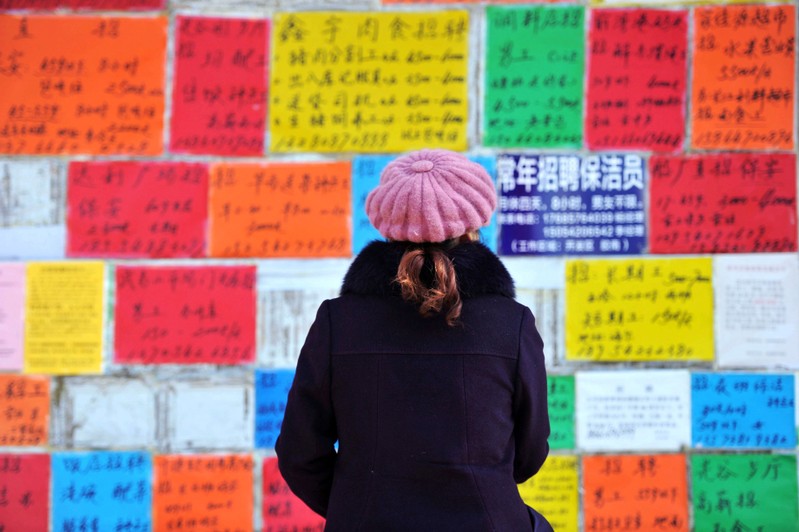 Woman looks at job advertisements on a wall in Qingdao West Coast New Zone
