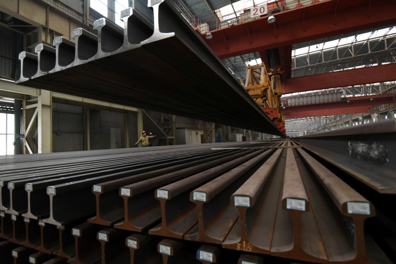 FILE PHOTO: A worker directs a crane lifting steel rails at a steel factory in Handan