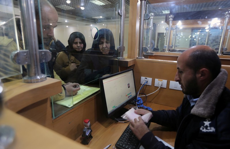 Palestinian Hamas-hired police officer checks the documents of people upon their return from Egypt, at Rafah border crossing in the southern Gaza Strip