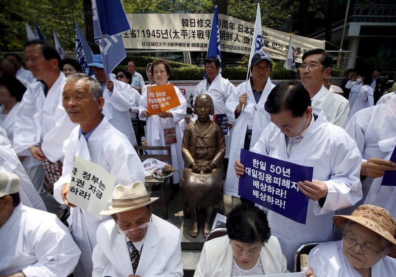FILE PHOTO: Descendants of Koreans who were conscripted to the Japanese imperial army or recruited for forced labor under Japan's colonisation surround a statue of a girl as they attend an anti-Japan rally in front of the Japanese embassy in Seoul