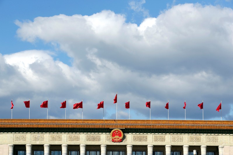 Red flags flutter on the top of the Great Hall of the People in Beijing