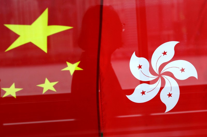 FILE PHOTO - A woman is reflected in a window behind Chinese and Hong Kong flags after celebrations commemorating the 20th anniversary of Hong Kong's handover to Chinese sovereignty from British rule, in Hong Kong