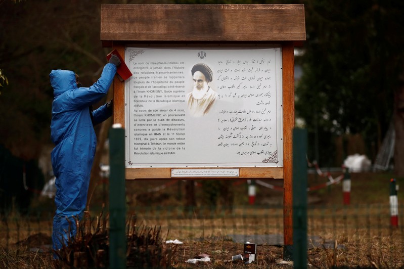 A worker cleans an information board written in French and Persian next to the entrance of the garden where Iran's late leader Ayatollah Ruhollah Khomeini used to pray during his four month exile in Neauphle-le-Chateau