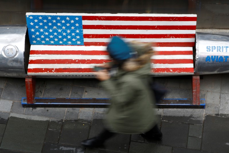 Woman walks past a bench painted in the colours of the U.S. flag outside a clothing store in Beijing