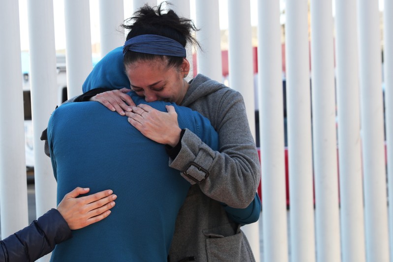 People embrace near the Chaparral border crossing in Tijuana, Mexico