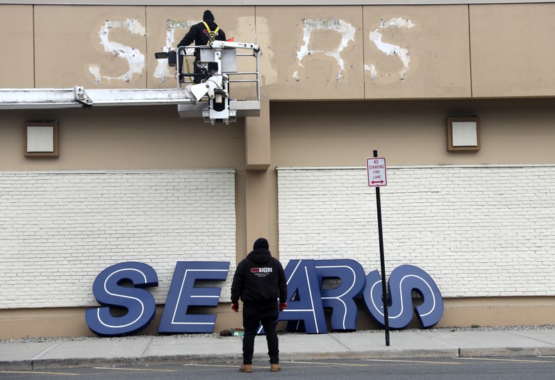 Workers remove a sign from the outside of a Sears department store in Nanuet