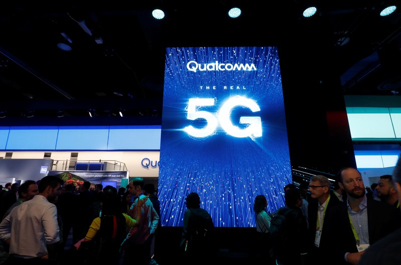 People walk by a video display promoting 5G connectivity at the Qualcomm booth during the 2019 CES in Las Vegas
