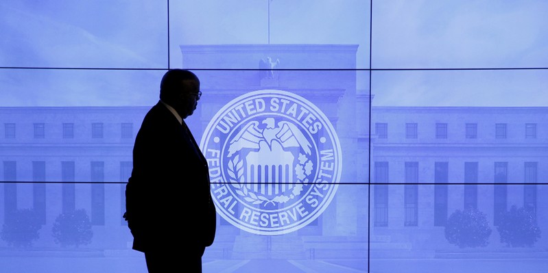 FILE PHOTO: FILE PHOTO: A guard walks in front of a Federal Reserve image before press conference in Washington