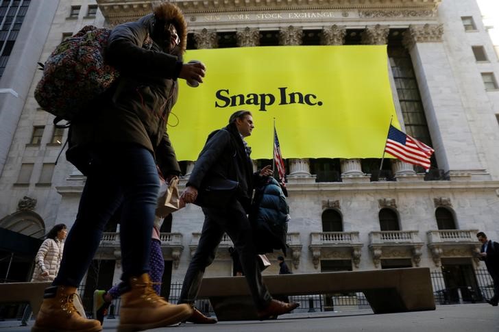 FILE PHOTO - Pedestrians walk past the front of the New York Stock Exchange (NYSE) with a Snap Inc. logo hung on the front of it shortly before the company's IPO in New York