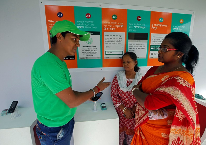 A WhatsApp-Reliance Jio representative explains how to use Facebook Inc's WhatsApp messenger to a woman during a drive by the two companies to educate users, on the outskirts of Kolkata