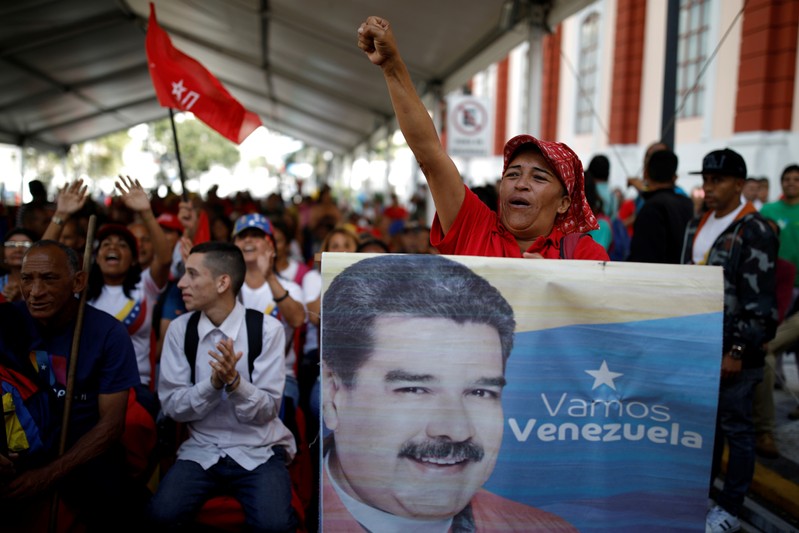 FILE PHOTO: A supporter of Venezuela's President Nicolas Maduro holds a banner depicting him as he takes part in a gathering outside the Miraflores Palace in Caracas,