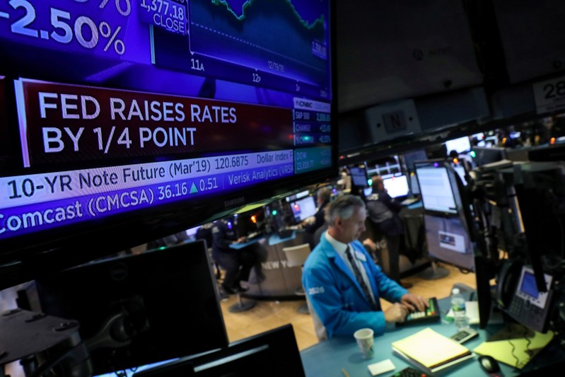 FILE PHOTO: A screen displays the headlines that the U.S. Federal Reserve raised interest rates as a trader works at a post on the floor of the NYSE in New York