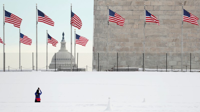 The U.S. Capitol is seen as a Jogger photographs the Washington Monument