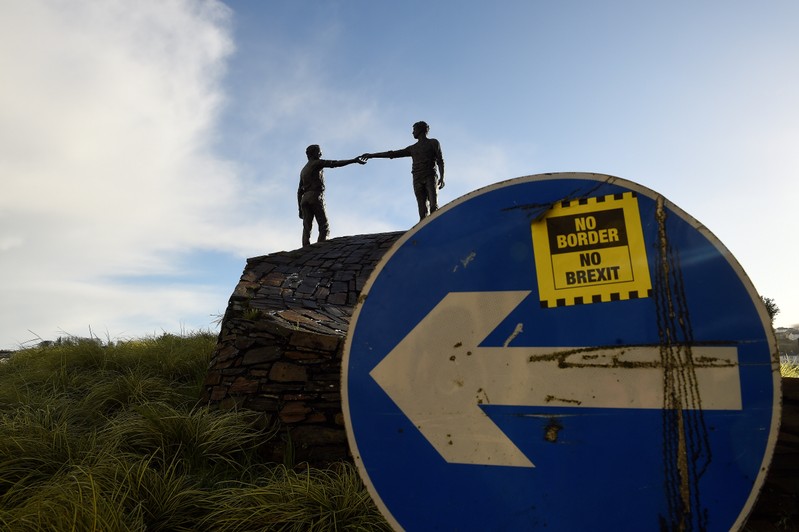 FILE PHOTO: A ' No Border, No Brexit' sticker is seen on a road sign in front of the Peace statue entitled 'Hands Across the Divide' in Londonderry