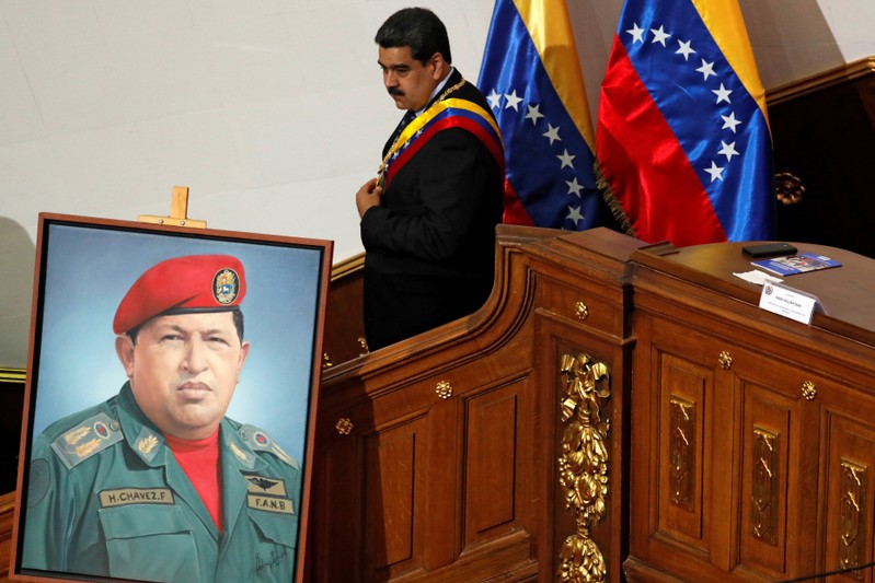 FILE PHOTO: Venezuela's President Nicolas Maduro walks next to a painting of Venezuela's late President Hugo Chavez, during a special session of the National Constituent Assembly to present his annual state of the nation in Caracas
