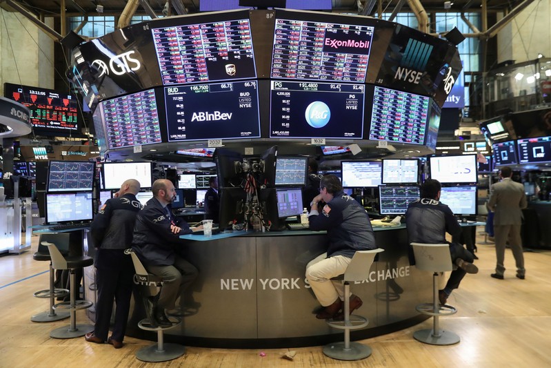 Traders look at price monitors as they work on the floor at the New York Stock Exchange (NYSE) in New York City