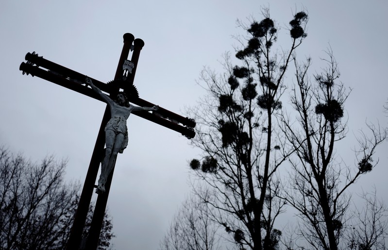 A cross is seen near trees with mistletoe near the church in Kalinowka