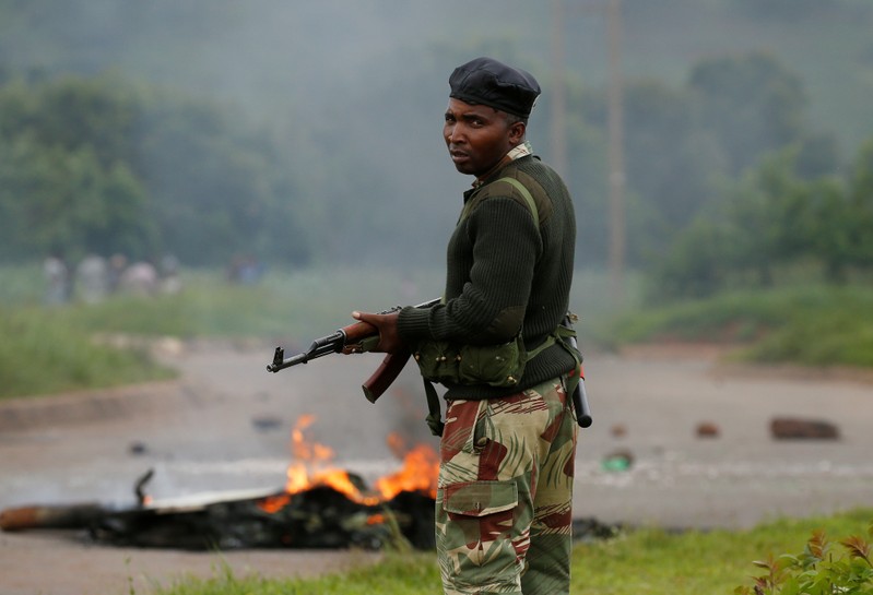 FILE PHOTO: A soldier stands before a burning barricade during protests in Harare