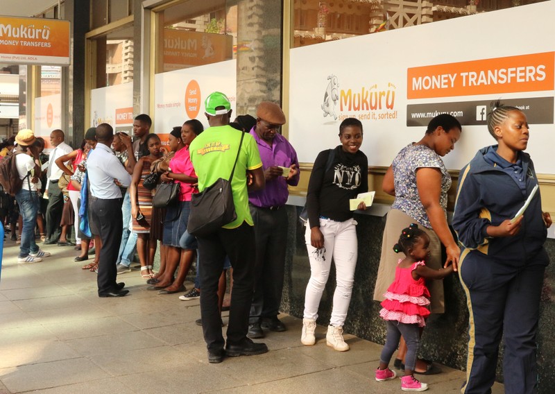 People queue to withdraw US dollars from a money transfer shop in Harare