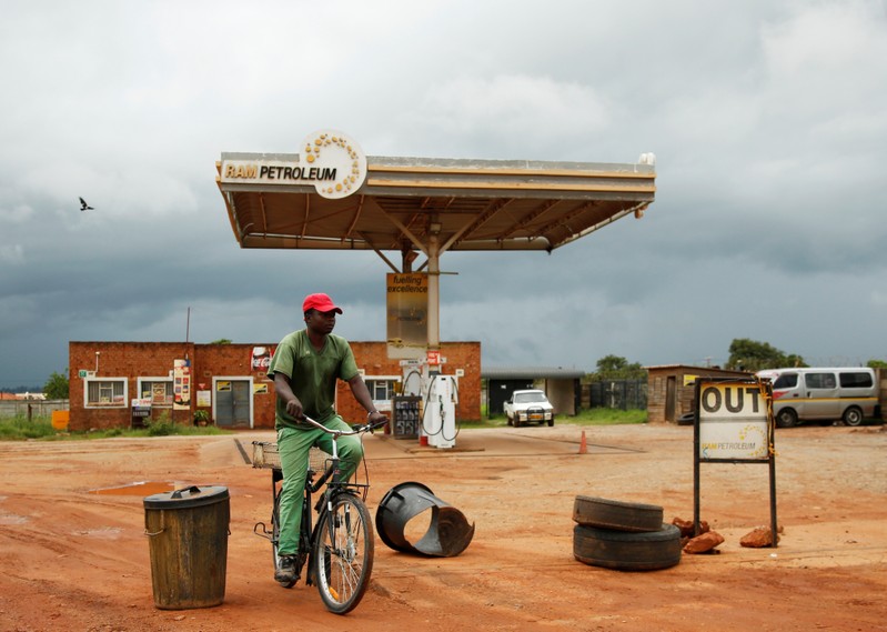 A man cycles past a petrol station closed after protests in Harare