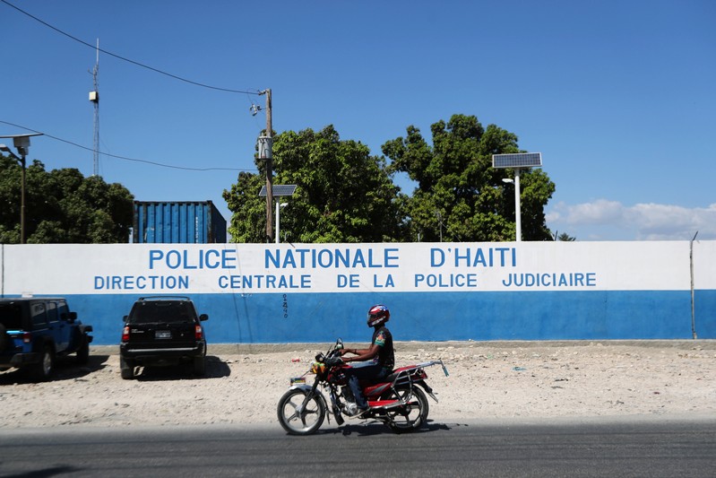 A man rides a bike in front of a main Haitian police station, where a group of foreign nationals including Americans are detained after finding them armed with semi-automatic weapons after a week of anti-government protests in Port-au-Prince